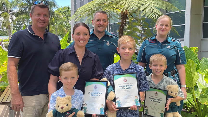 family and paramedics with children holding awards