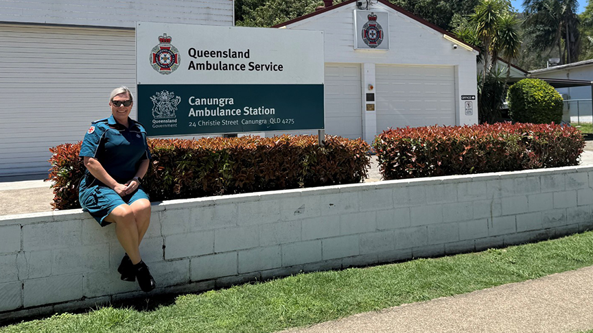 Paramedic sits on a wall in front of ambulance station